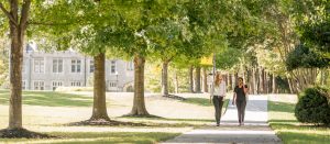 Two young women walk along the tree-lined quad.